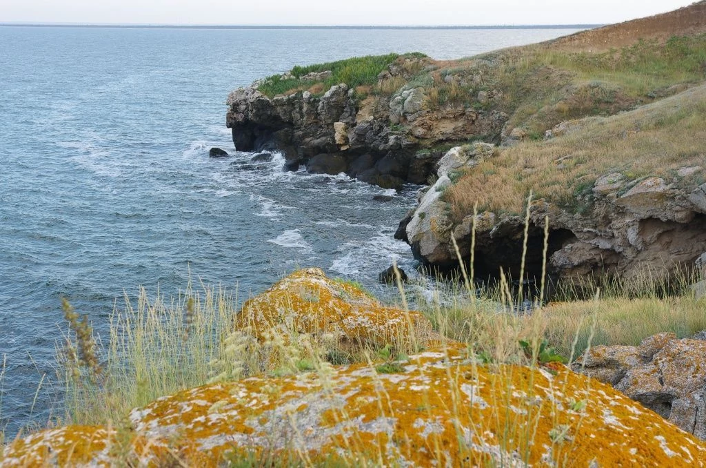 Казантип сложен из светло-серых мшанковых известняков, покрытых оранжевыми пятнами лишайников Казантип сложен из светло-серых мшанковых известняков, покрытых оранжевыми пятнами лишайников
